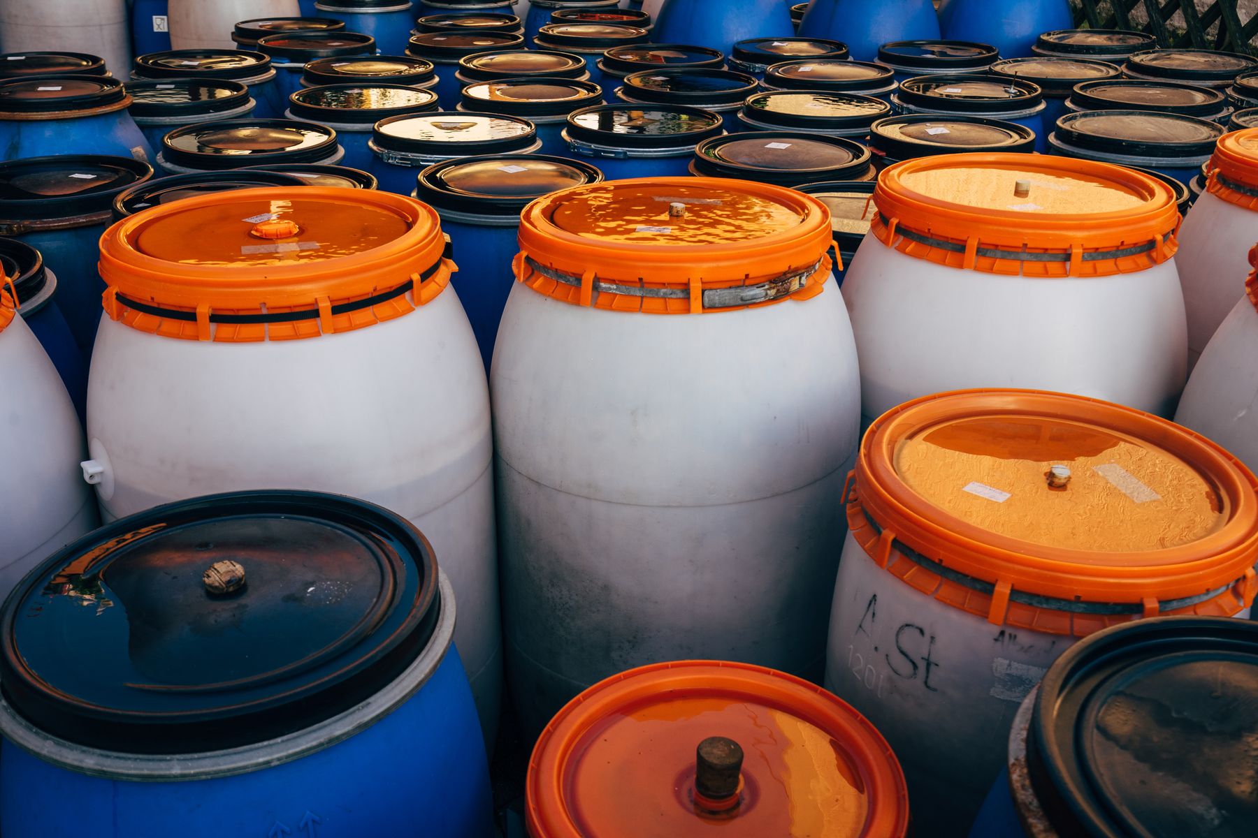 White plastic chemical drums with orange locking-ring lids